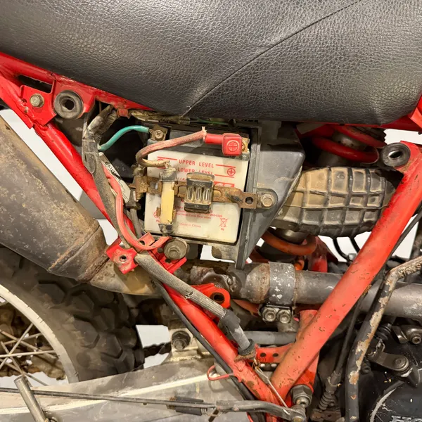 Under the seat, left side, as found. Regulator and CDI mounted to the frame, with a previous owner's wiring and tape in evidence.
