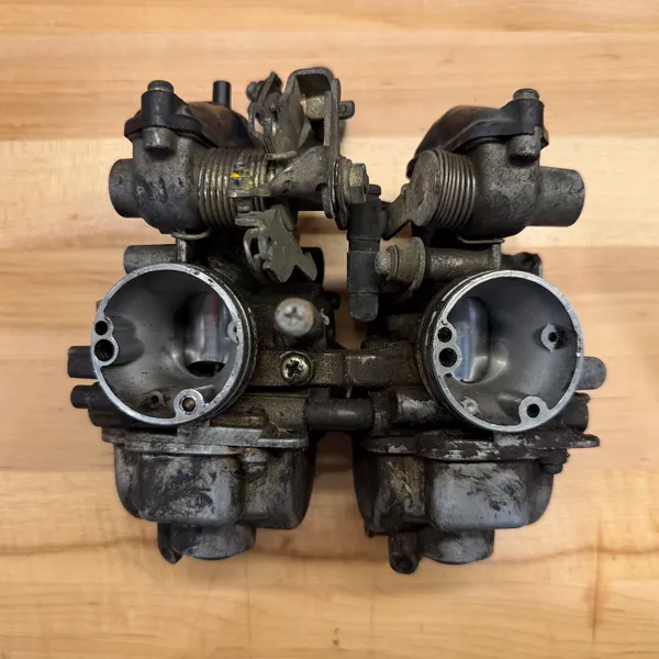 The complete dual carb assembly, engine side. Primary carb on the left, secondary on the right, joined by the linkage and the fuel crossover.