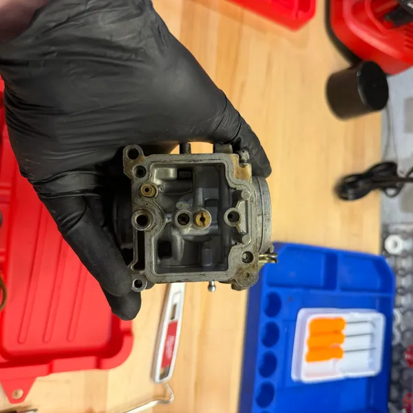 Float bowl off. Float, float valve and main jet visible. Varnish, but not the worst I've seen.