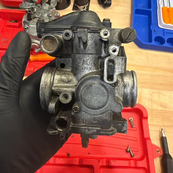 Primary carb body, engine side. The large bore and the idle mixture screw boss.