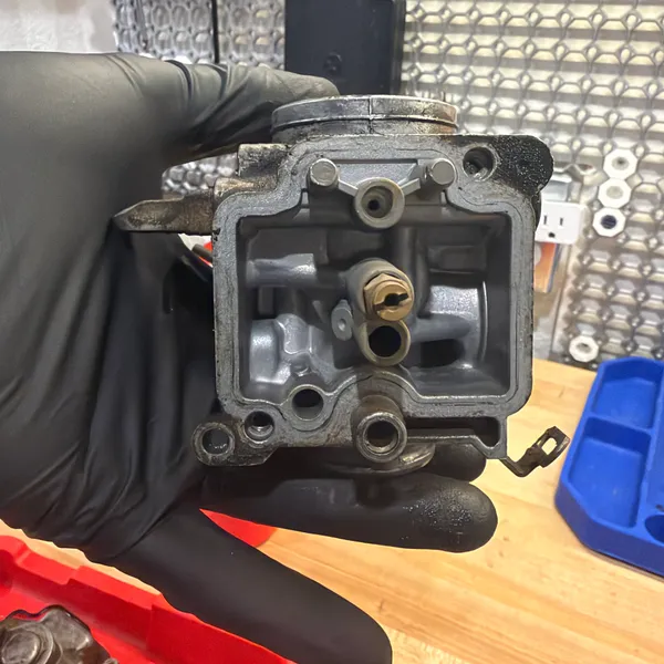 Float bowl cavity on the primary with the float removed. Float valve seat and main jet holder visible.