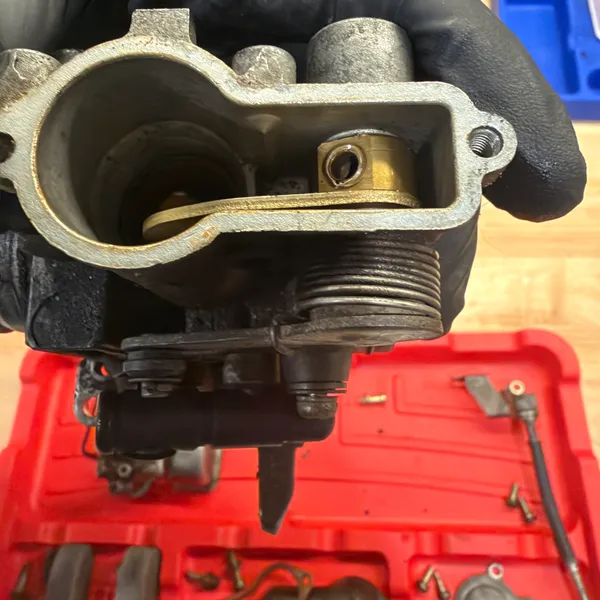 Secondary float bowl cavity. Brass float, pivot pin, and the float valve with its spring clip.