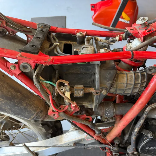 Under the seat, left side: the CDI box and regulator on their rubber mounts, harness along the frame rail.