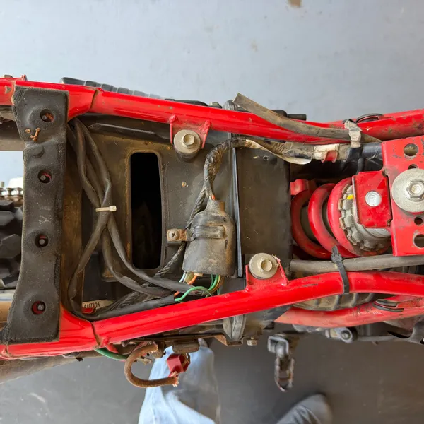 Battery box from above, battery removed. Wiring to the right, the airbox snorkel behind.