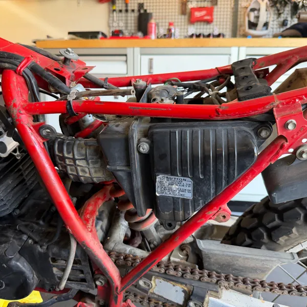 Right side under the seat. Airbox outer wall, the black box is the CDI unit, rear brake light switch wiring below.