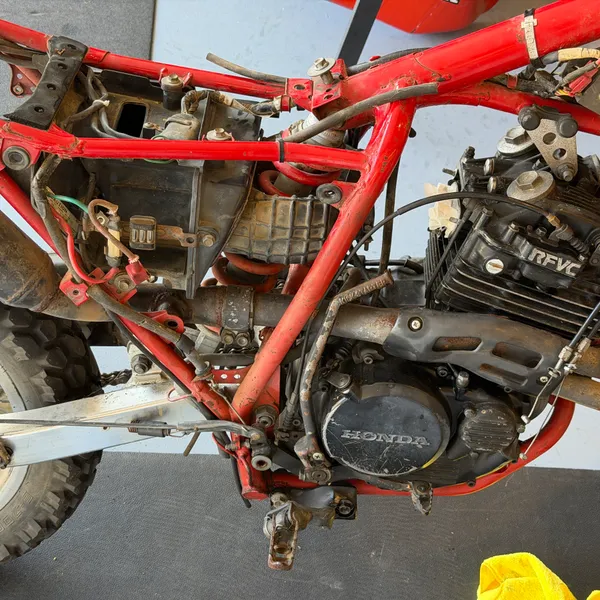 Same side, slightly wider. Footpeg, kickstarter, header pipe still on.