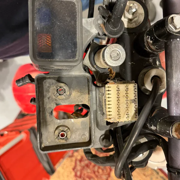 Pod bracket and the connector from above. Two bolts hold the bracket; the connector just clips into the headlight shell.