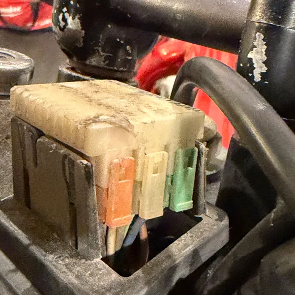 The big white multi-pin connector block, as found. Dust, corrosion on the pins, and a pink and green wire pair going in the side.