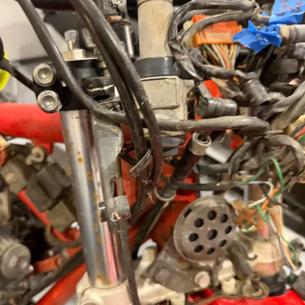 Fork top and upper triple clamp with the headlight stay. Blue tape with a note on the harness so I know what goes where later.