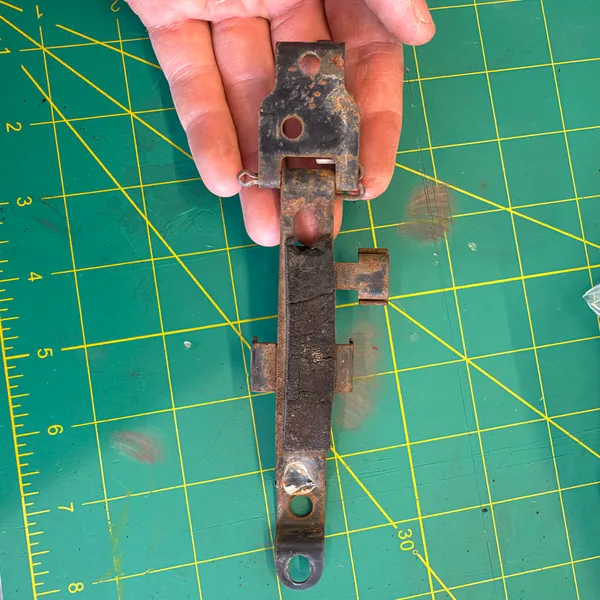 Headlight bracket off the bike, rusty and bent at the lower ear.