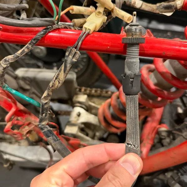Same cable, held up. The braided outer sheath is original; the rubber boot at the adjuster end is split.