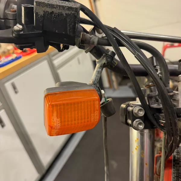 Left front turn signal on its rubber stalk, mounted to the headlight stay. Lens is sun-faded but not cracked.