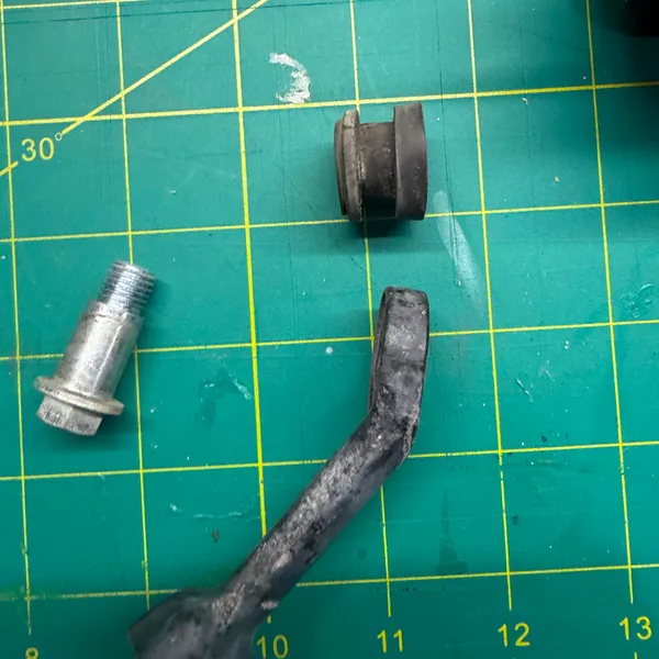 The stalk apart: rubber-covered arm, the metal bushing it pivots on, and the shoulder bolt. The rubber is cracked where it flexes.