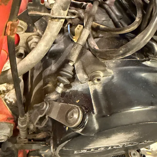Right side: rear brake pedal, brake rod, and the brake light switch spring, with the right engine cover behind.