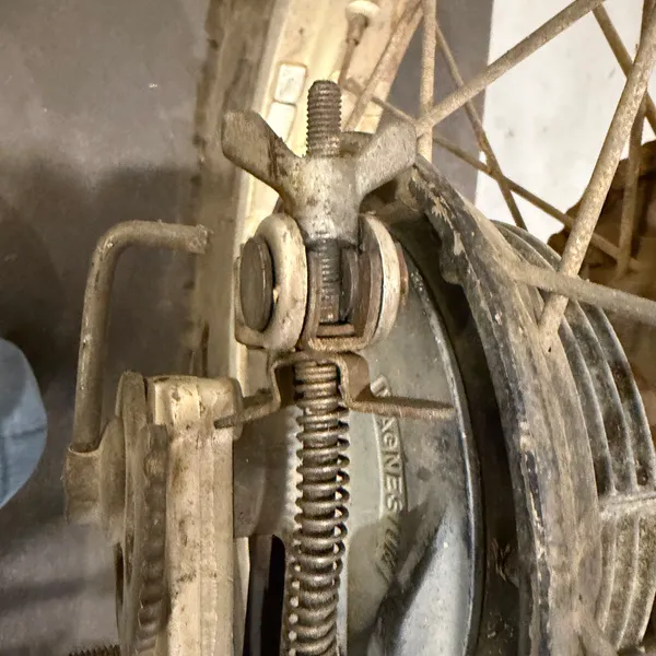 Rear brake arm and adjuster at the drum, with the return spring. Adjuster wing nut still turns.