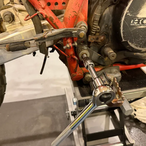 Ratchet on the brake pedal pivot nut, with the right footpeg bracket above.