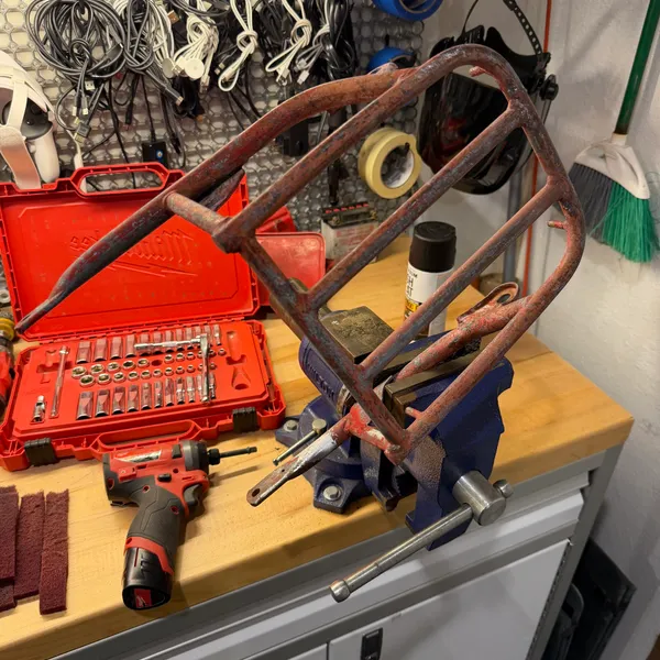 Rear rack in the vise for rust removal. Rotary tool and sanding pads.